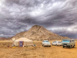 Three Vehicles Beside Mountain Under Cloudy Sky