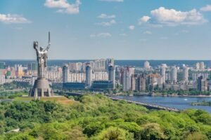 Motherland Monument among green trees on embankment in Kiev