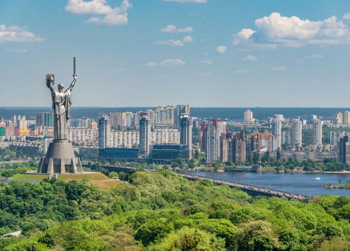 Motherland Monument among green trees on embankment in Kiev