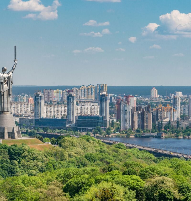 Motherland Monument among green trees on embankment in Kiev