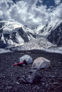 Person Sitting Beside a Tent on Mountain Area