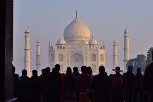 Silhouetted tourists admire the Taj Mahal's iconic beauty at sunrise, a UNESCO World Heritage site.