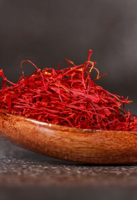 Detailed close-up of vibrant saffron threads in a wooden spoon, perfect for culinary imagery.