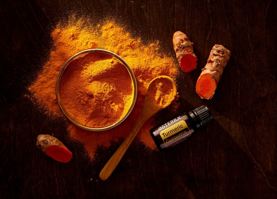 Vista superior de polvo de cúrcuma, raíces de cúrcuma y aceite esencial sobre superficie de madera.