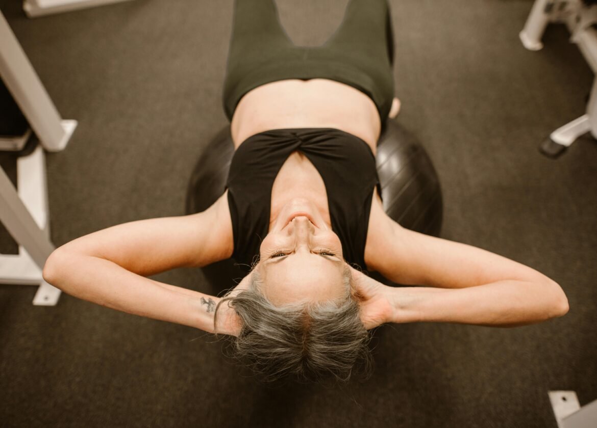 Senior woman performing exercise on stability ball for fitness and strength.